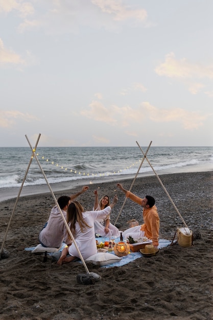 Foto gratuita amici in spiaggia con cibo e bevande