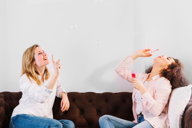 Friends blowing bubbles on sofa