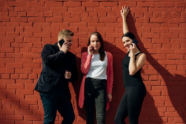 Friends calling on phones leaning on wall