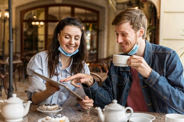 Friends chatting in the restaurant while having medical masks on their chin