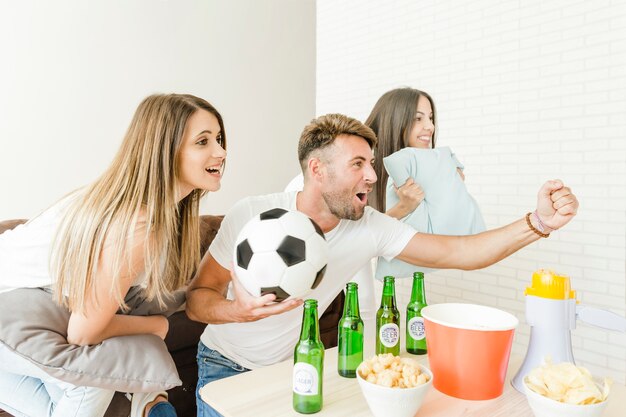 Friends cheering watching football at home