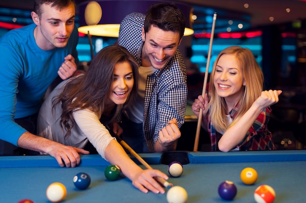 Free photo friends cheering while their friend aiming for billiards ball