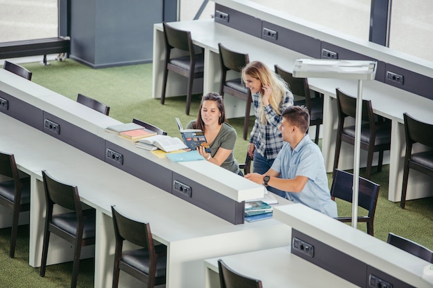 Friends in college library with books