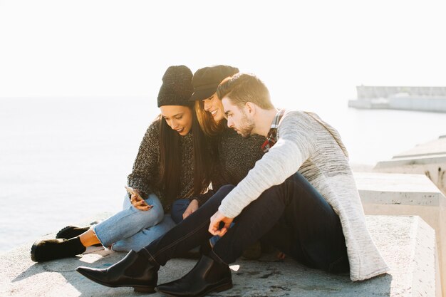 Friends on concrete blocks looking at smartphone