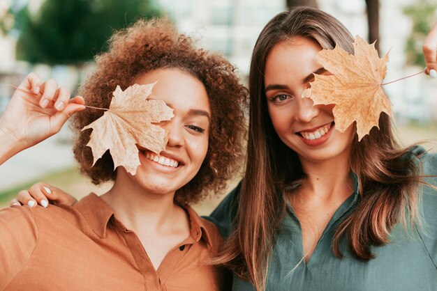 Free photo friends covering their eyes with a dry leaf