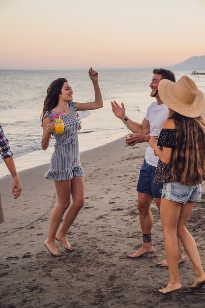 Друзья танцуют на пляже на закате
