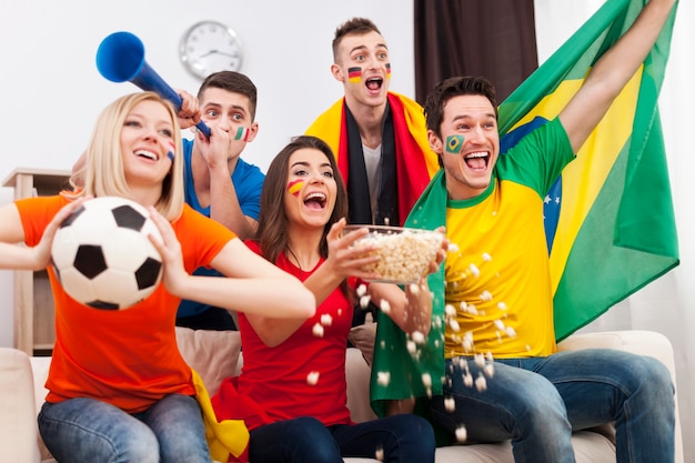 Friends of different nations celebrating goal of favourite team