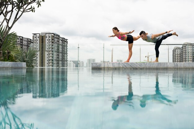 Friends doing yoga together by the pool