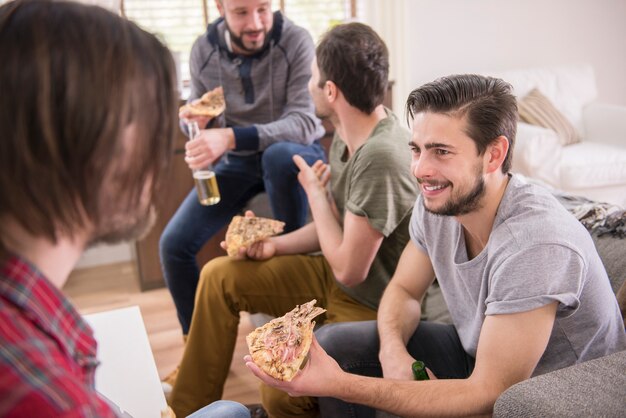 Amici che bevono birra e mangiano pizza