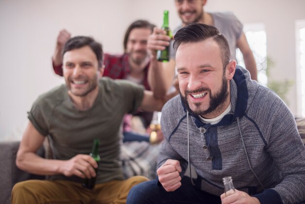 Friends drinking beer and watching football match