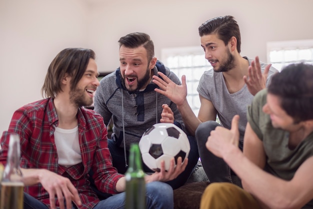 Друзья пьют пиво и смотрят футбольный матч