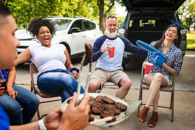 Free photo friends drinking and eating at a tailgate party