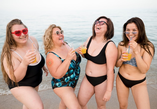 Friends drinking juice at the beach front view