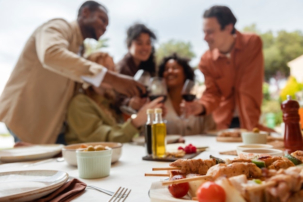 Foto gratuita amici che bevono vino e mangiano barbecue durante la festa all'aperto