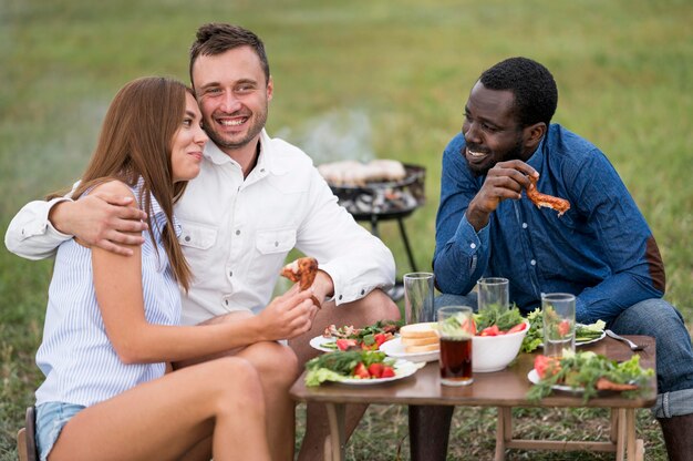 Friends eating next to barbecue outdoors