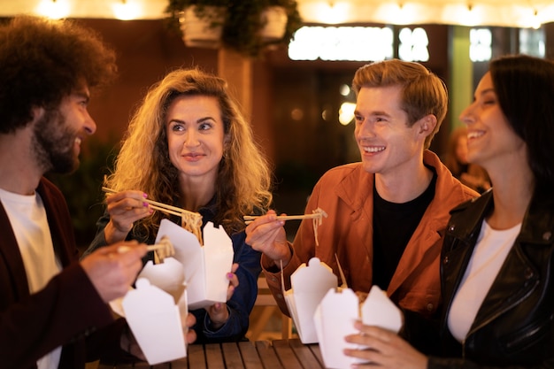 Foto gratuita amici che mangiano cibo cinese insieme durante una serata fuori