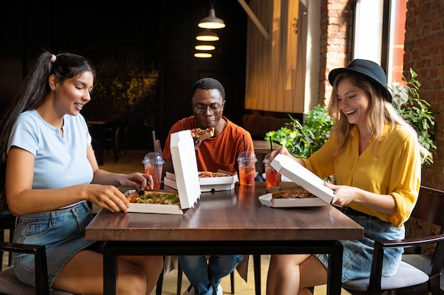 Free photo friends eating pizza medium shot