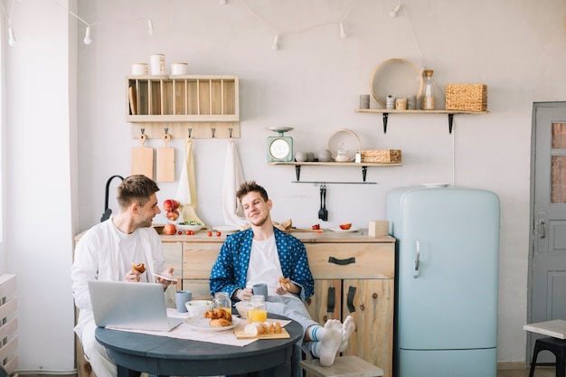 Friends enjoying breakfast sitting in front of table in kitchen