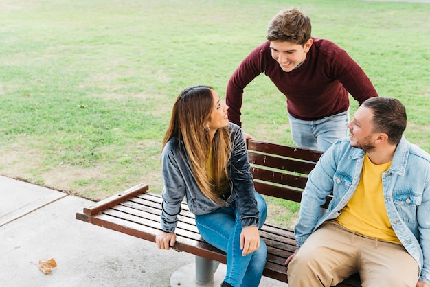 Free photo friends enjoying day in park sitting on bench