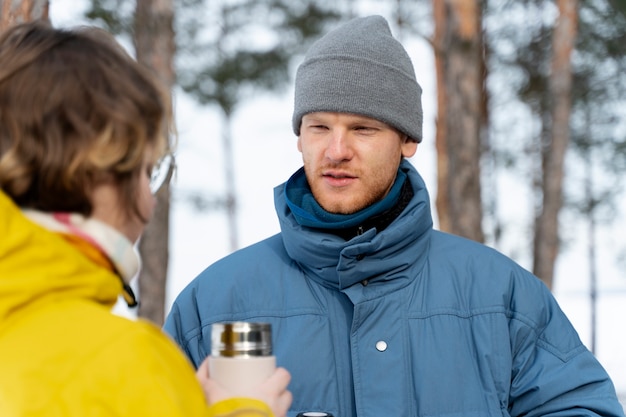 Friends enjoying hot drink while on winter trip