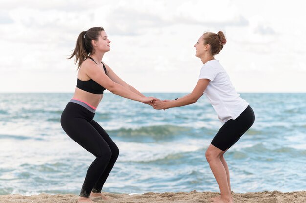 Friends exercising at beach side view