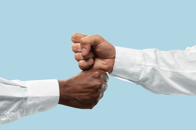 Friends greetings sign or disagreement. Two male hands competion in arm wrestling isolated on blue  background.