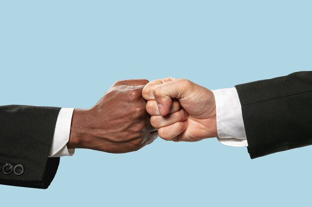 Friends greetings sign or disagreement. Two male hands competion in arm wrestling isolated on blue background.