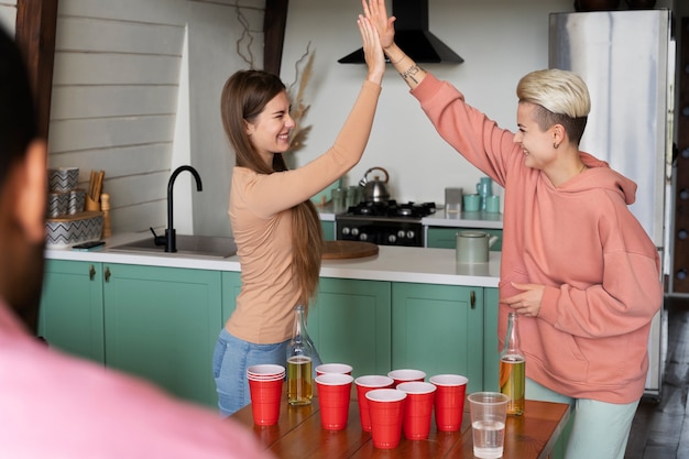 Friends high-fiving each other over a beer pong game