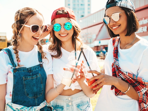 Friends holding and drinking fresh cocktail smoothie drink in plastic cup with straw