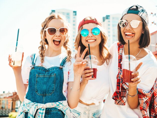 Friends holding and drinking fresh cocktail smoothie drink in plastic cup with straw