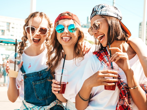 Friends holding and drinking fresh cocktail smoothie drink in plastic cup with straw