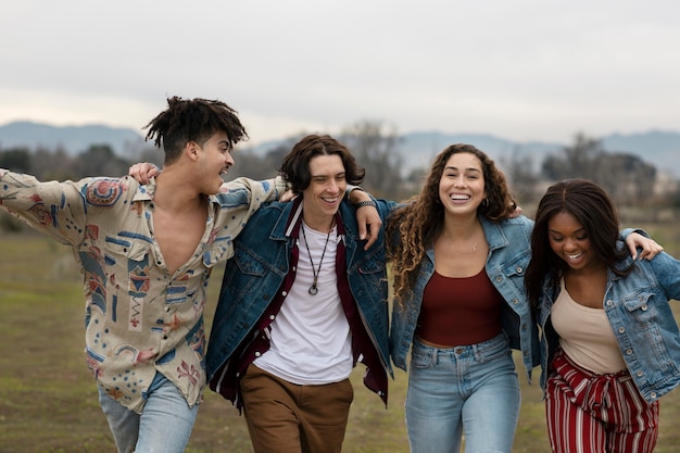 Free photo friends holding each other outdoors in a field