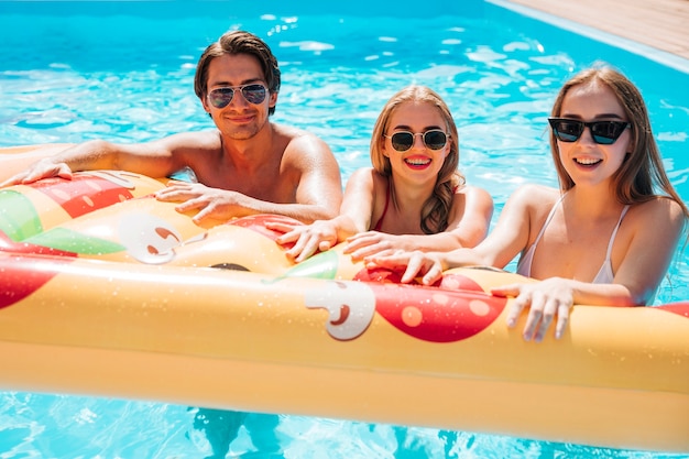 Friends holding pizza swimming float