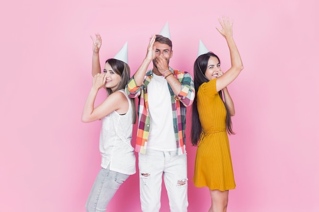 Friends holding their nose dancing on pink background