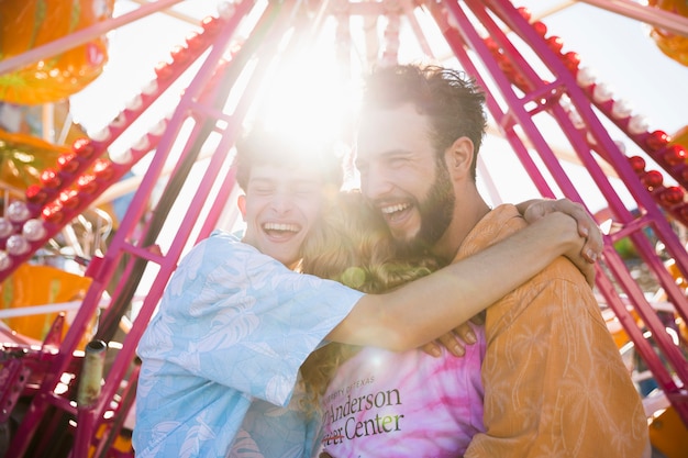 Amici che abbracciano alla luce del sole al luna park