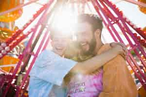 Foto gratuita amici che abbracciano alla luce del sole al luna park