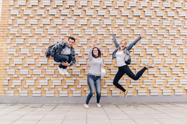 Free Photo | Friends jumping on brick wall