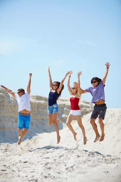 Friends jumping in the sand