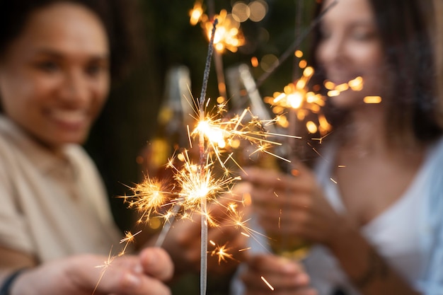 Friends outdoors in the park having beer and enjoying sparklers