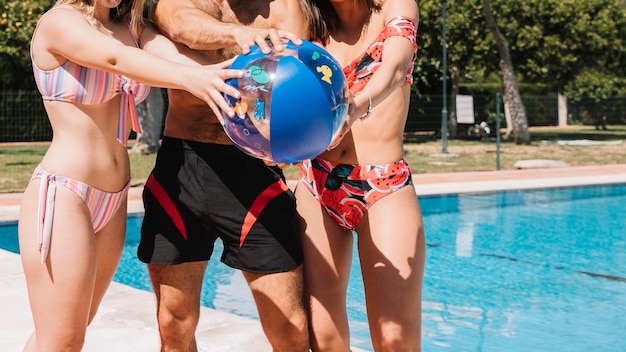 Friends playing ball next to pool