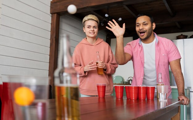 Friends playing beer pong together at a party