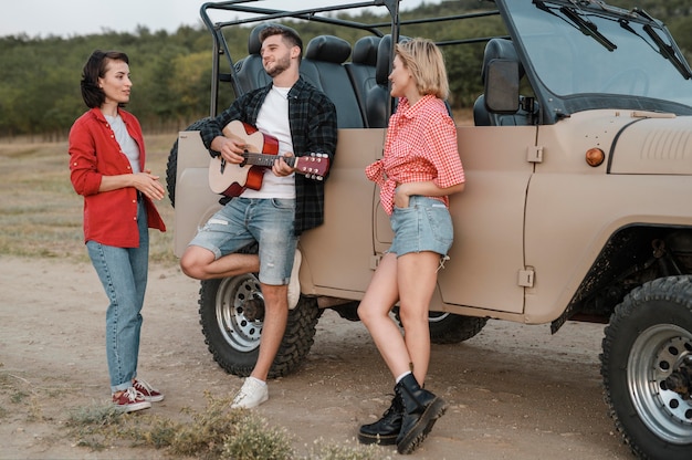 Friends playing guitar while traveling by car