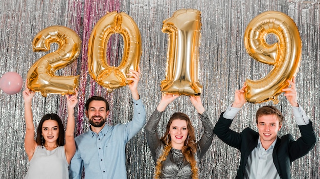 Free photo friends posing with golden balloons new year party