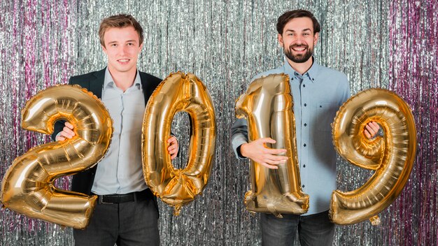 Friends posing with golden balloons at a new year party