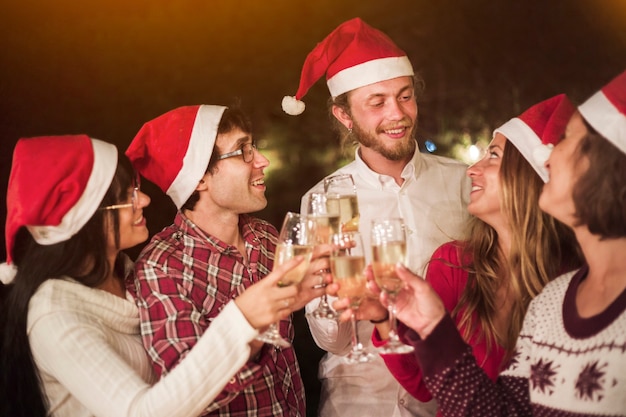 Free photo friends in santa hats clinking glasses at party