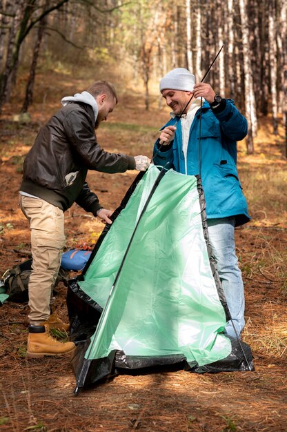 무료 사진 겨울 캠핑 텐트를 설정하는 친구들