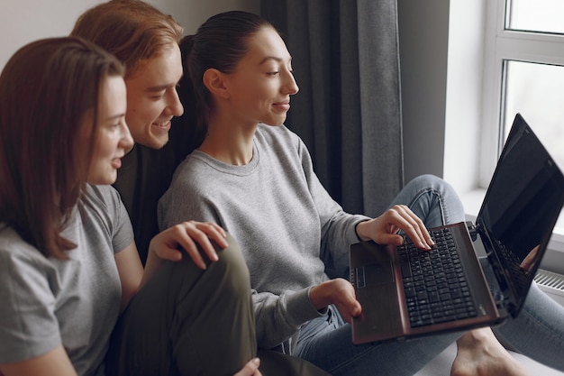 Friends sitting on a bed in a room and use a laptop