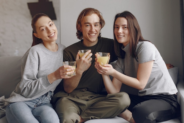 Friends sitting on a bed in a room with orange juice