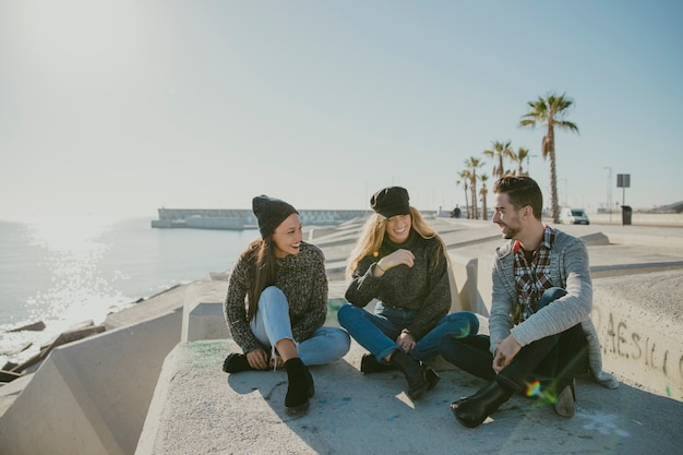 Free photo friends sitting by the sea