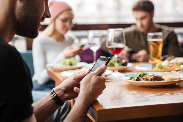 Друзья сидят в кафе и используют мобильные телефоны